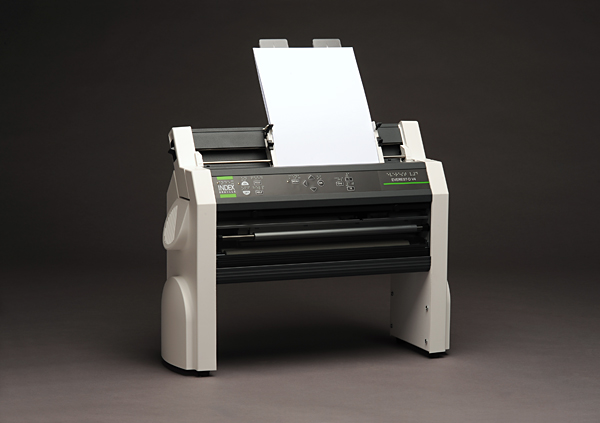 The Index Everest-D braille embosser, a beige desktop machine loaded with a sheet of paper, ready to emboss raised braille.